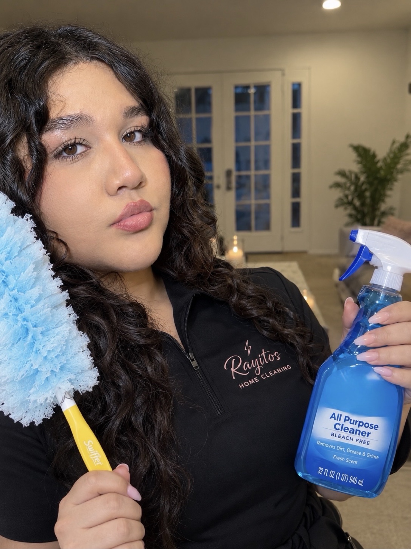 Housekeeper in uniform with a duster and spray bottle