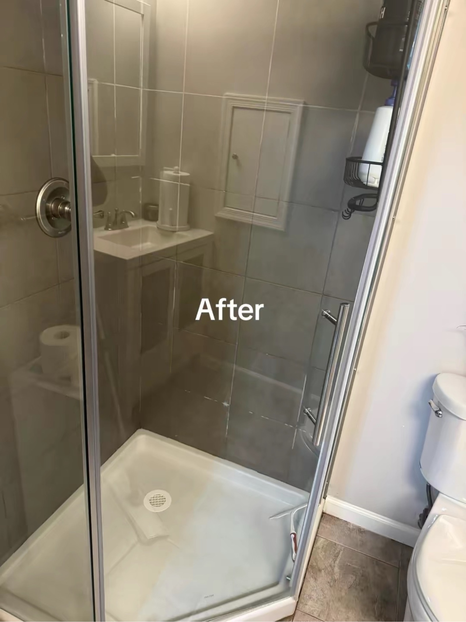 Hand in yellow glove cleaning shower glass with a squeegee